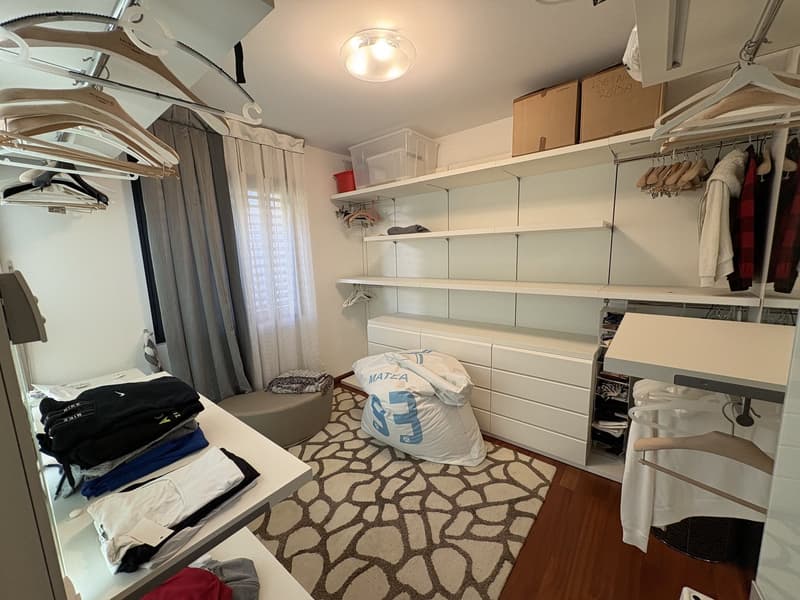 walk-in closet with shelves, carpet, storage bins, beanbag, tables with clothes