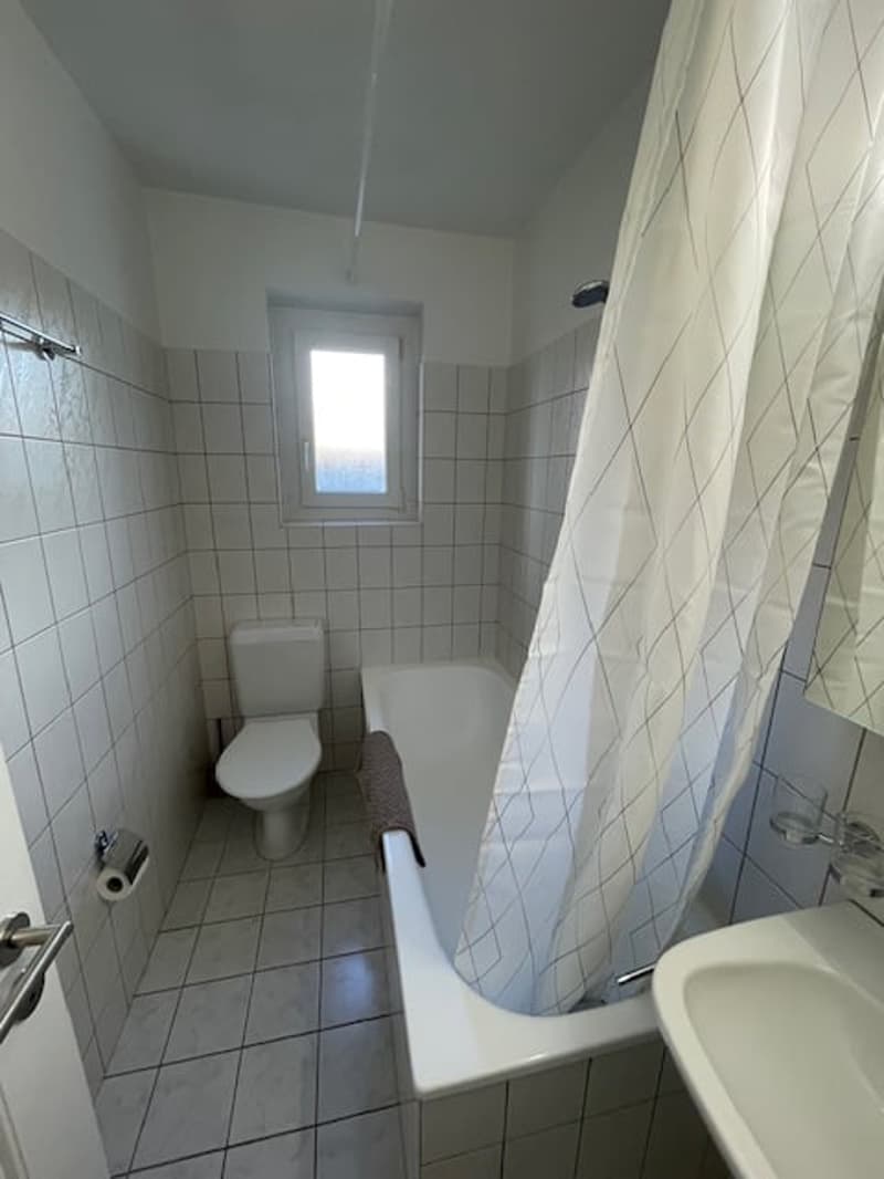 white bathroom with bathtub, toilet, sink, tiled walls and floor