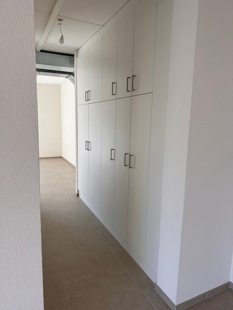empty hallway with beige tiles, tall white cabinets, and recessed lighting
