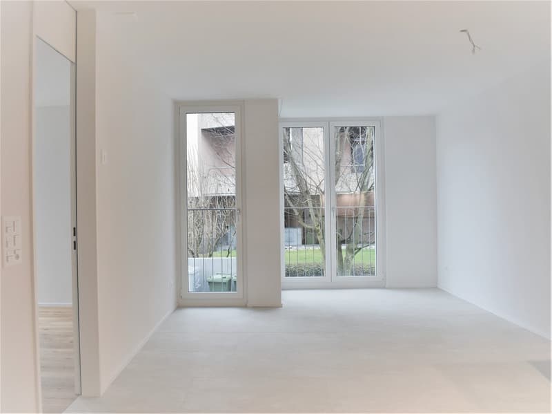 Large windows with glass doors leading to balcony, white walls, tiled floor