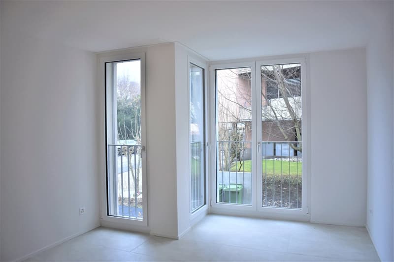empty room, white walls, white floors, 3 sliding glass doors with railings, electrical outlet