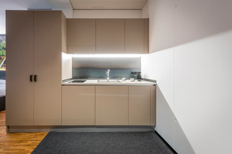 Compact kitchen with built-in cabinets, stainless steel sink, and dishwasher. The kitchen has a minimalist, modern design with neutral color tones.