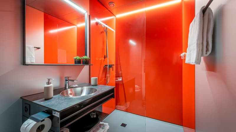 Bright orange bathroom with modern vanity, sink, and shower area