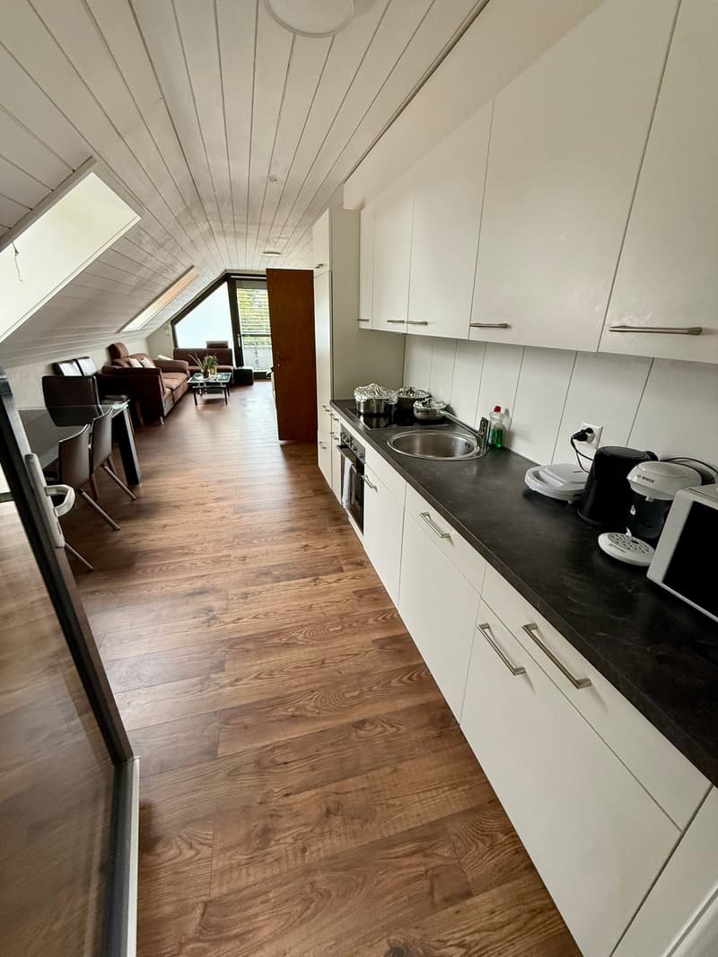 White cabinets, black countertops, glass door, appliances, wooden floor, dining table, living room view