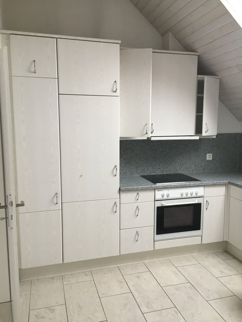 Fully equipped kitchen with modern appliances, white cabinets, gray tiled backsplash, and white tiled flooring.