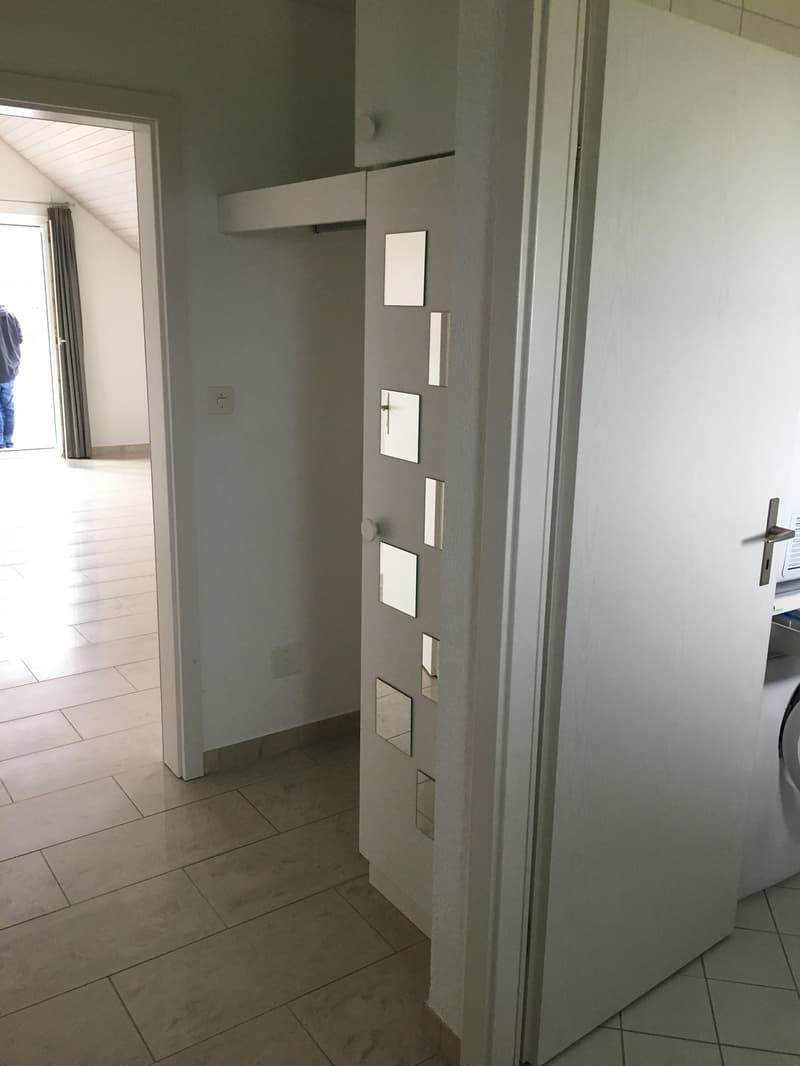 tiled floor, white walls, open door, door with mirror panels, washing machine inside the room