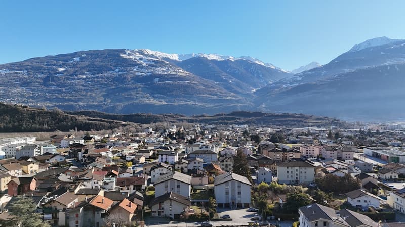 small town in the mountains, residential buildings, mountains in the background, snowy peaks