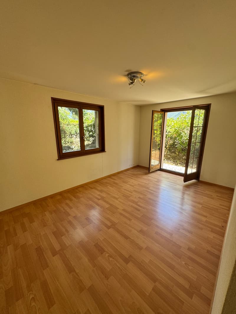 wooden floor, white walls, large window, sliding glass door leading to balcony, ceiling with ceiling light
