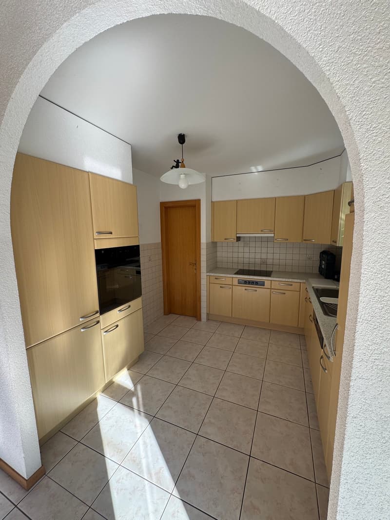 An empty kitchen with tiled floor, cabinets, microwave, stove, and sink