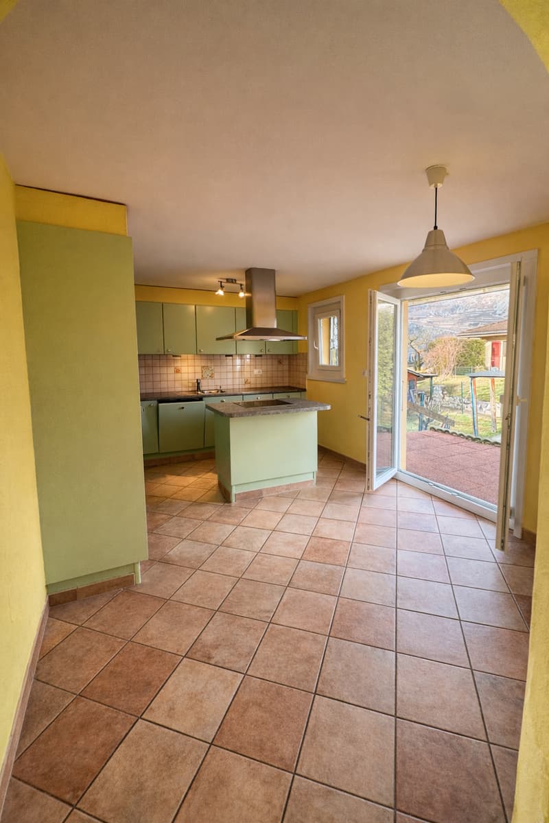 modern kitchen, central island, yellow walls, green cupboards, tile floor, open sliding doors to patio