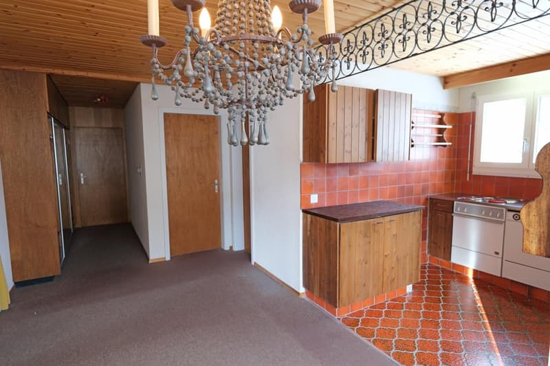 Chandelier, wooden cabinetry, tiled backsplash, modern oven, wooden flooring