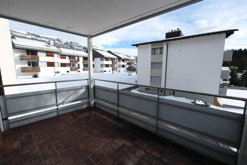 Outdoor terrace with railings, tiled floor, mountain view in the distance