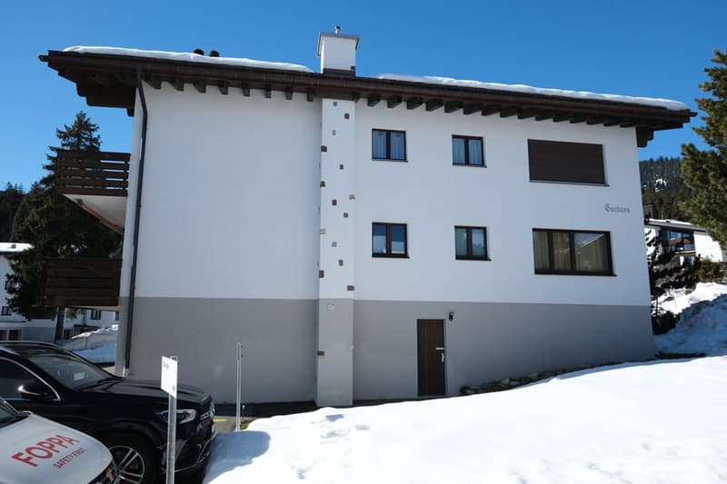 white and gray building, 3 floors, balcony, snow on the roof, cars parked in front