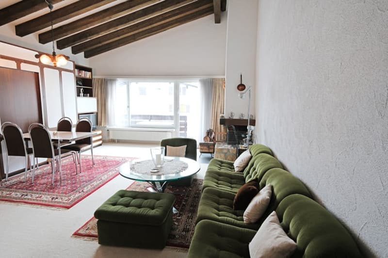 green couch, coffee table, dining table, chairs, fireplace, wooden ceiling
