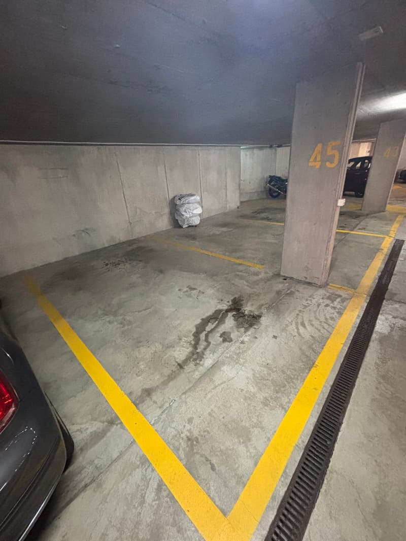 underground parking garage, concrete floor, yellow parking lines, car parked