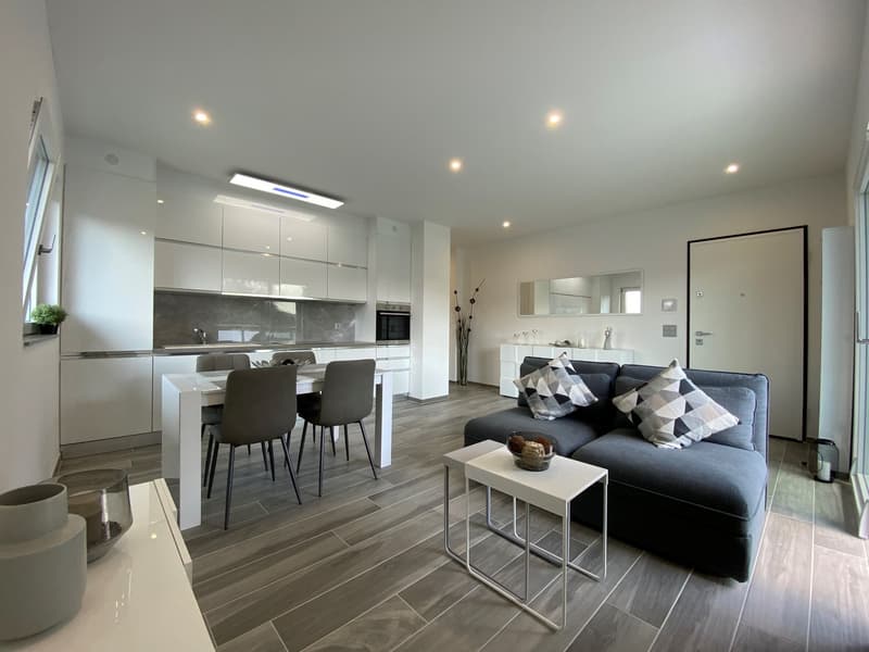 modern living room with dining area, white kitchen, wooden floor, gray couch, white table, gray chairs