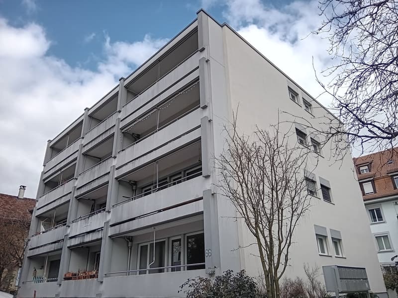 multi-story building, white exterior, balconies on each floor, modern design, multiple windows, metal railings