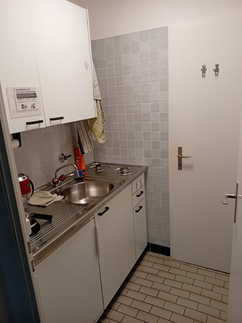 small kitchen with sink, stove, cabinets, tiled floor, white walls