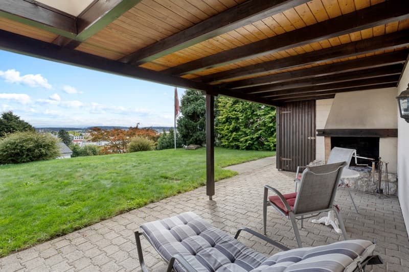 Fireplace, outdoor seating, covered patio, brick paving, lush green lawn, view of the horizon