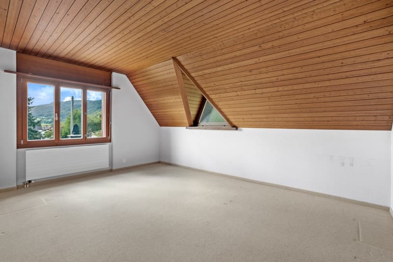 Empty attic room with beige carpet, wooden ceiling, windows with mountain view