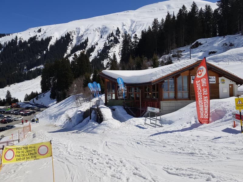 Alpine building in snowy mountain landscape with snow ramps, flags, and ski tracks