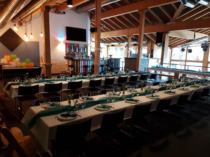A large open dining area, decorated tables, high ceilings, wooden beams, tables set for service.