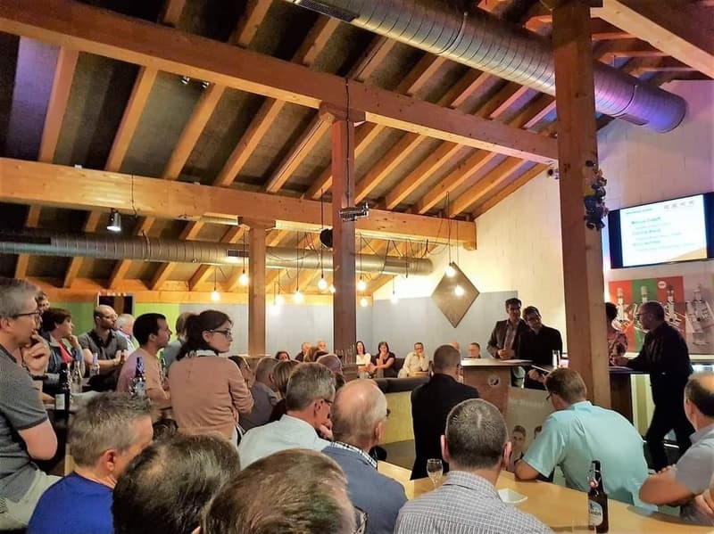 a restaurant with wooden ceiling, exposed wooden beam, tables, and a stage with a microphone