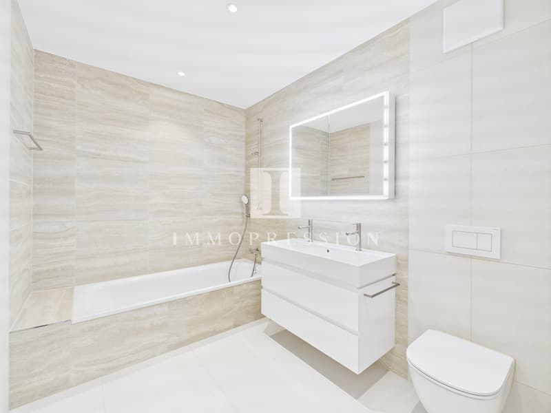 modern bathroom with bathtub, white tiles, white vanity, white toilet, mirror