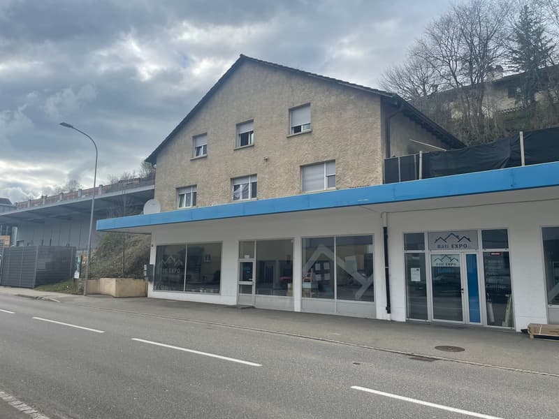 two-story building with a blue awning, multiple windows, commercial space, sign reading 'BâtI EXPO'