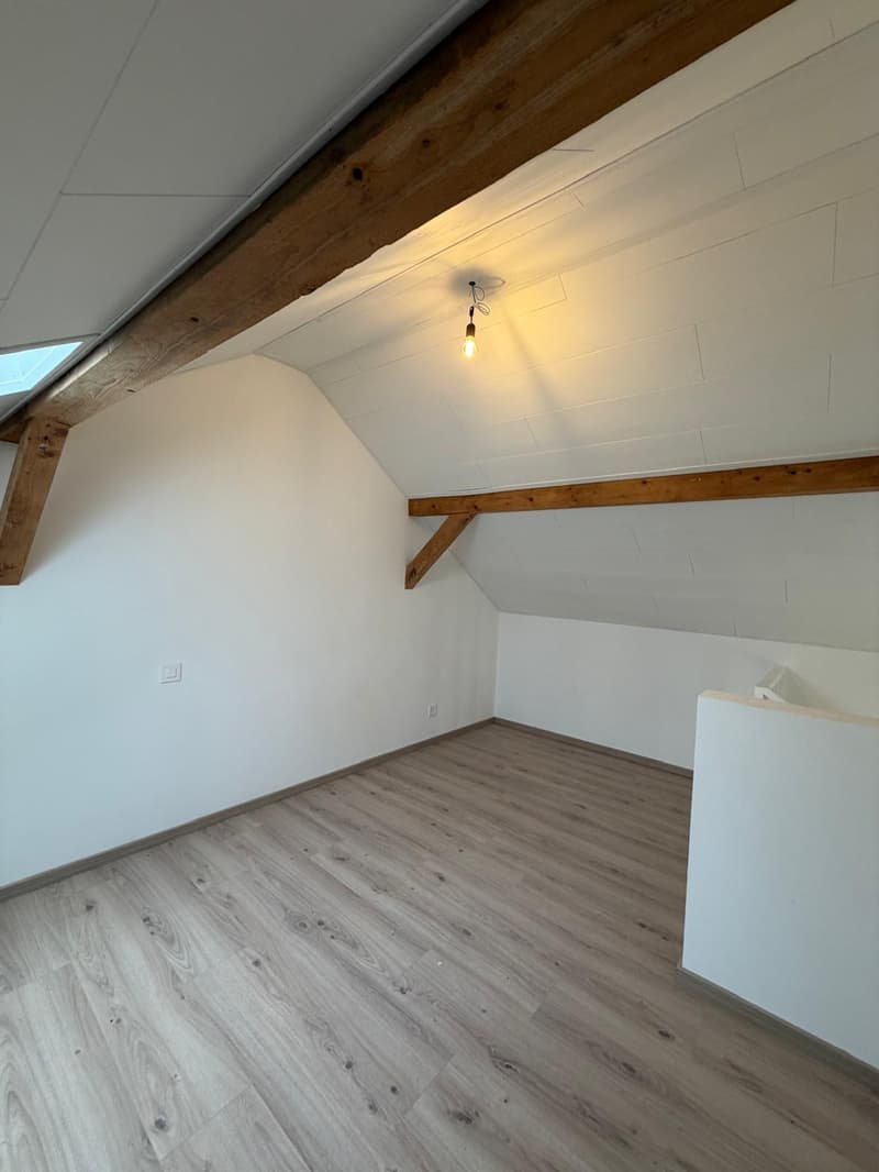 empty room with wooden ceiling, wooden floor, white walls, exposed brick wall
