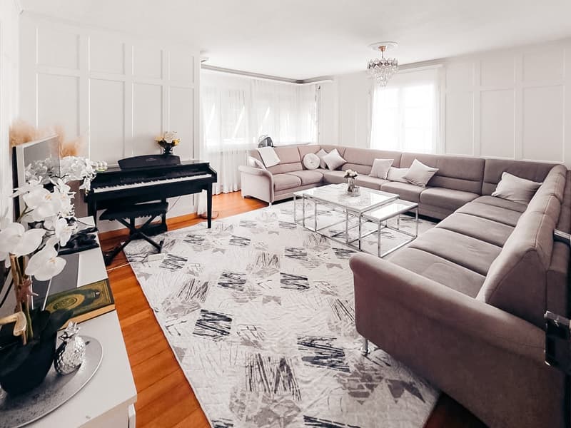 living room with a piano, couch, coffee table, rug, and chandelier