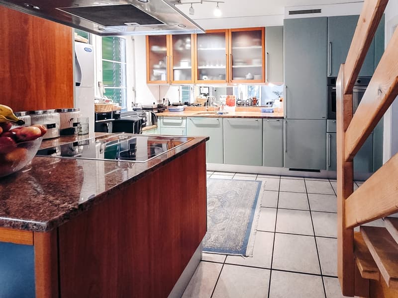 modern kitchen with wooden cabinets, granite countertop, gas stove, refrigerator, sink, wooden stairs