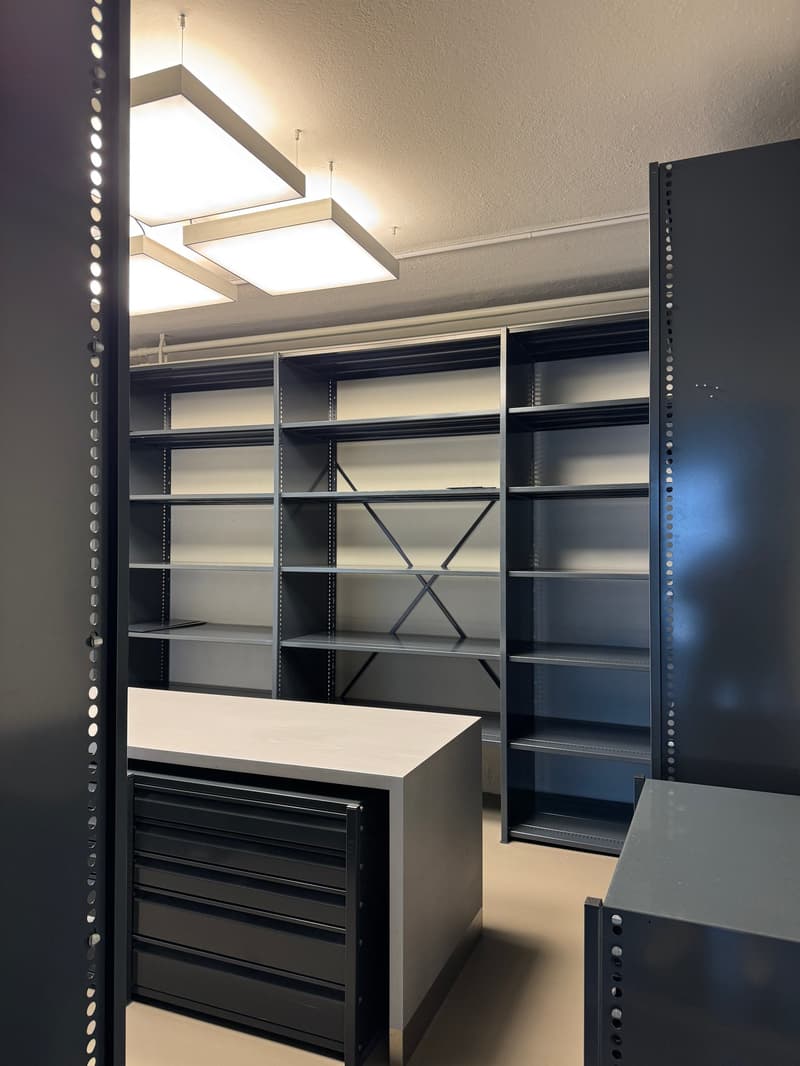Empty room with large metal shelves, metal drawers, and a metal table