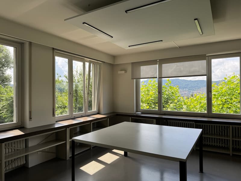 large windows, white table, white ceiling, white walls, radiators, wooden benches