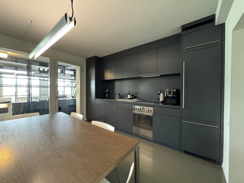 modern kitchen with wooden table, black cabinets, stainless steel appliances, large windows