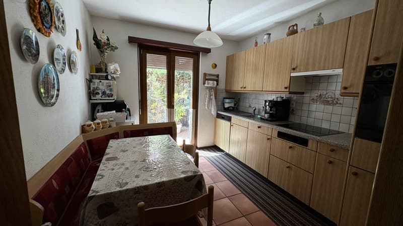 Spacious kitchen with wooden cabinets, tiled backsplash, dining table, and dishwasher visible