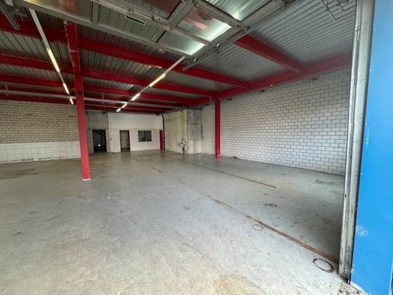 empty warehouse, metal ceiling, brick walls, wide doors, red pillars
