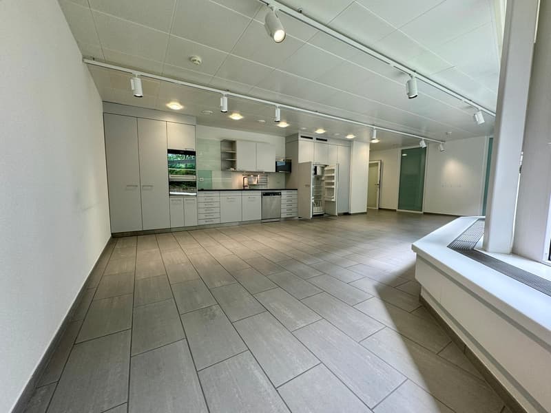 Spacious open-plan kitchen with modern gray cabinets, stainless steel appliances including a dishwasher, and a tiled floor.