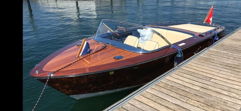 Wooden boat, brown color, glass windshield, leather seats, flags, dock
