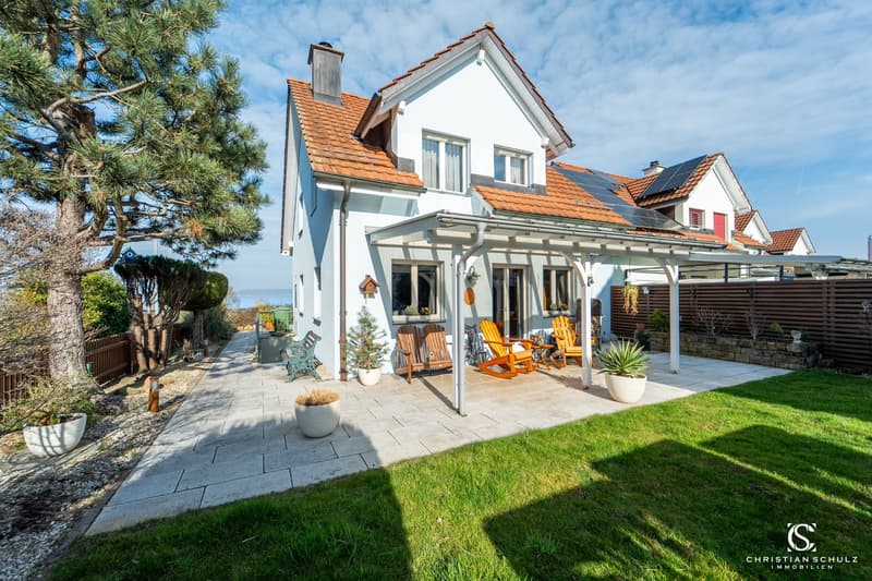 white house, red roof, solar panels, terrace with chairs, garden with plants and trees