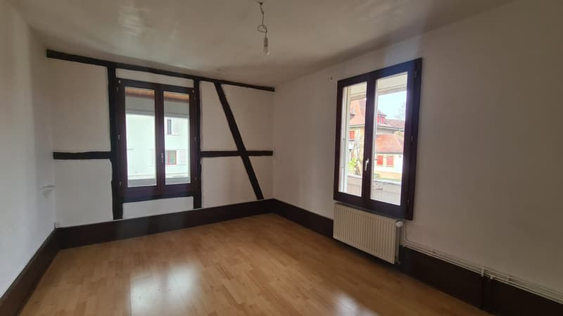 wooden floor, white walls, two windows with wooden frames, white radiator
