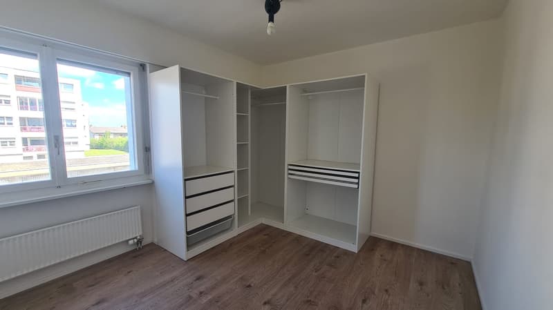 empty room, white wardrobe, wooden floor, large window, white walls, white radiator