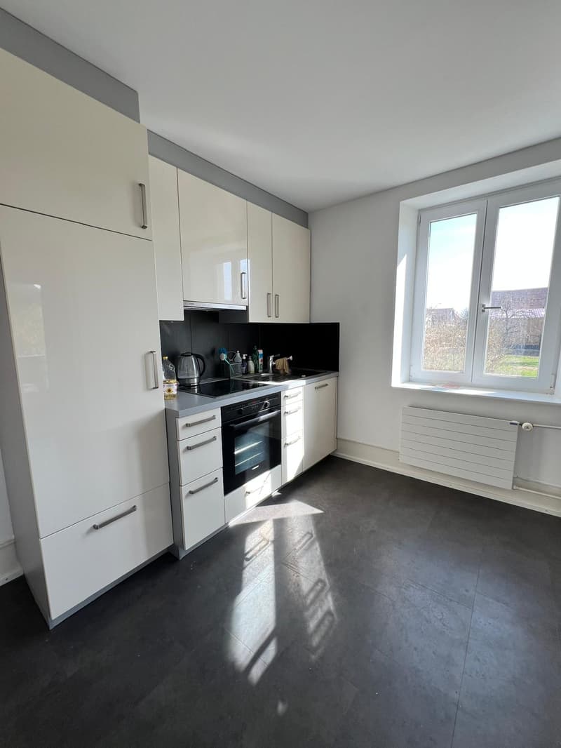 modern kitchen with white cabinets, gray floor, large window, built-in oven and stove