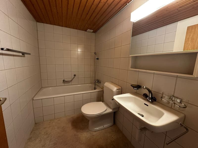 Bathroom with bathtub, toilet, sink, mirror, and wooden ceiling