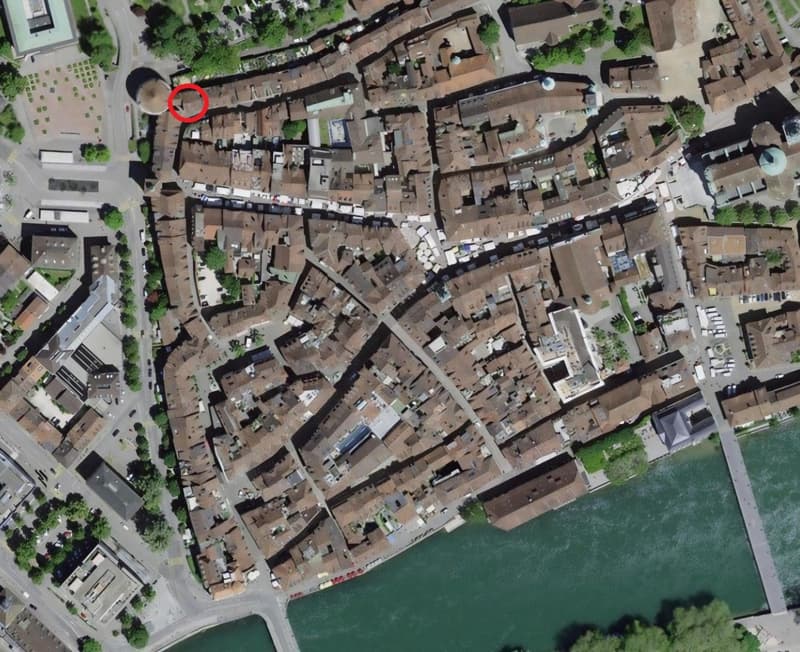 Densely built urban area with many buildings, narrow streets, and a river running through it.