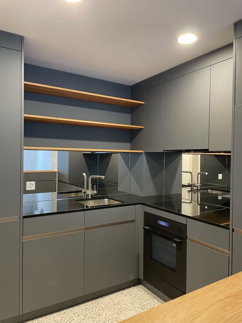 modern, gray kitchen with wooden countertop, black countertops, double sinks, stainless steel appliances