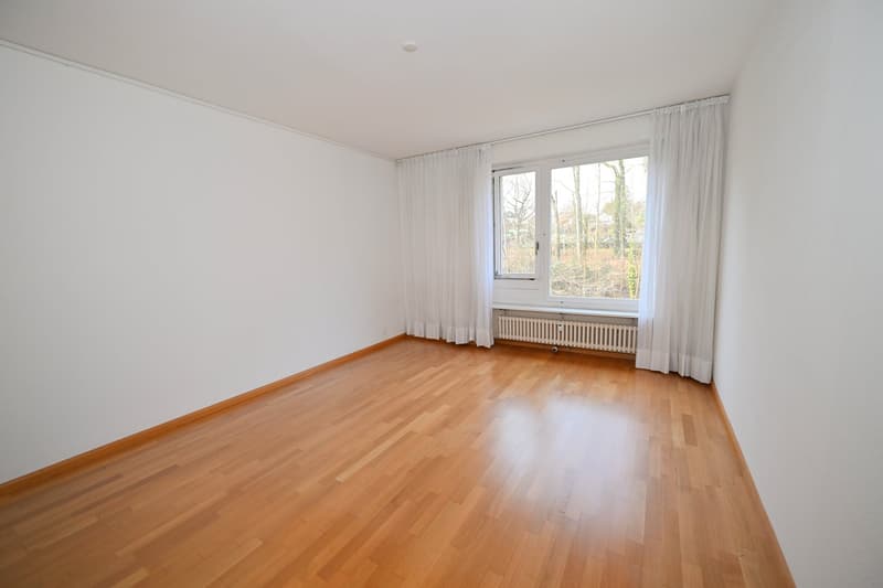 empty room, wooden floor, white walls, large window with white curtains, view of trees outside