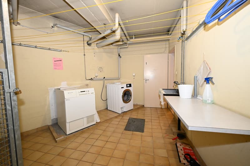 Laundry room with washing machine, dryer, and a table with cleaning supplies.