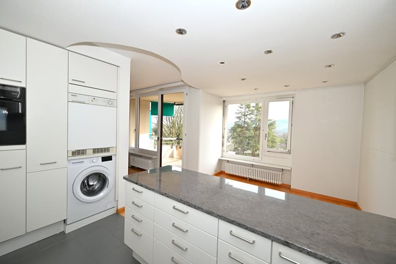 modern kitchen with white cabinets, granite countertop, washing machine, dishwasher, windows with balcony