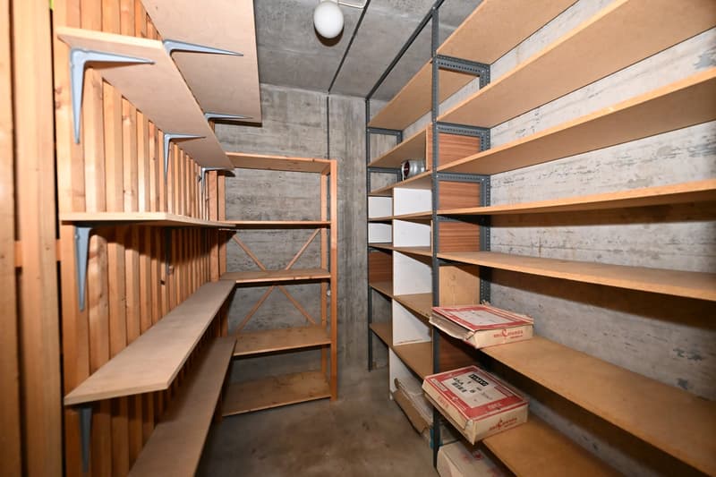 Storage room with wooden shelves, metal brackets, and a hanging light